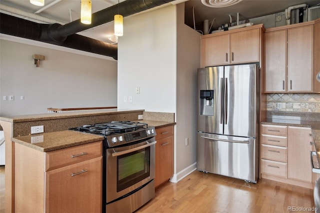 kitchen featuring stone counters, appliances with stainless steel finishes, hanging light fixtures, light hardwood / wood-style floors, and light brown cabinets