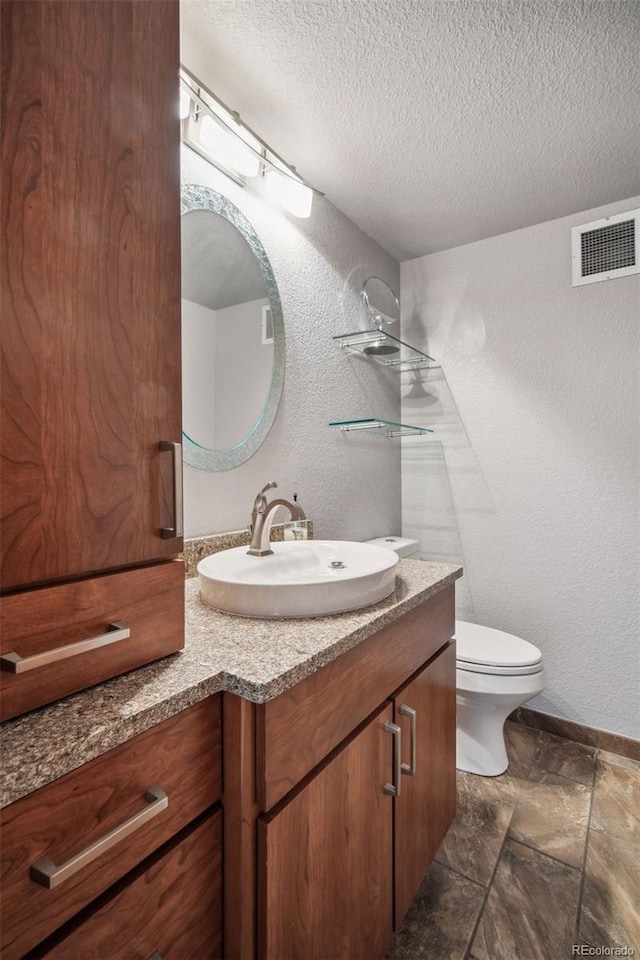 bathroom with vanity, toilet, and a textured ceiling