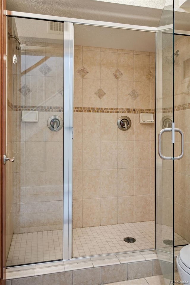 bathroom featuring a shower with door and toilet