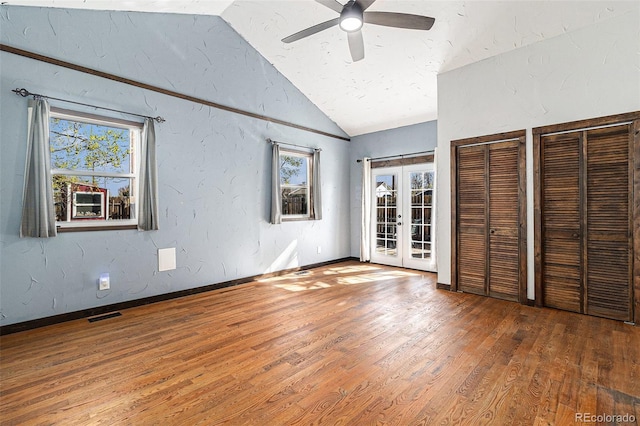unfurnished bedroom with multiple windows, french doors, lofted ceiling, and visible vents