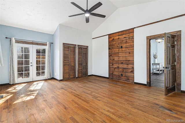 unfurnished bedroom featuring vaulted ceiling, baseboards, french doors, and wood finished floors
