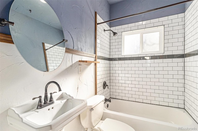 bathroom with toilet,  shower combination, and a sink