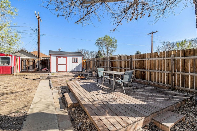 wooden terrace featuring outdoor dining area, an outbuilding, a shed, and a fenced backyard