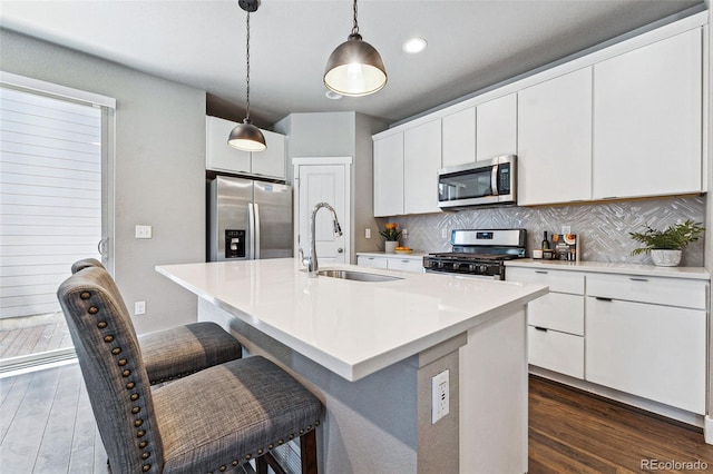 kitchen with an island with sink, appliances with stainless steel finishes, sink, and white cabinets