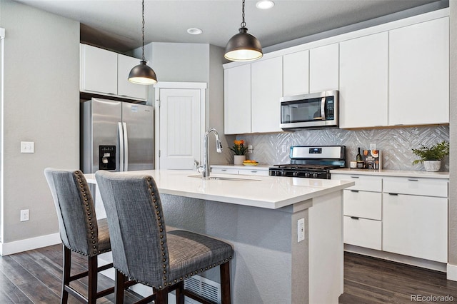 kitchen with sink, white cabinetry, hanging light fixtures, a center island with sink, and stainless steel appliances