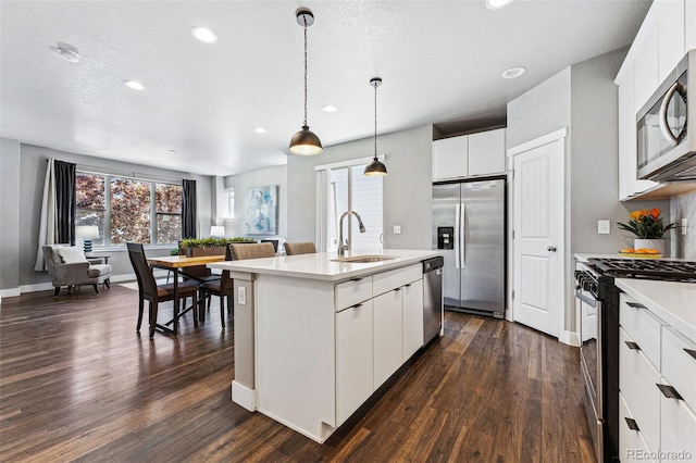 kitchen featuring sink, hanging light fixtures, appliances with stainless steel finishes, an island with sink, and white cabinets