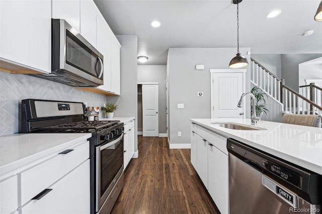 kitchen with stainless steel appliances, white cabinetry, sink, and decorative light fixtures