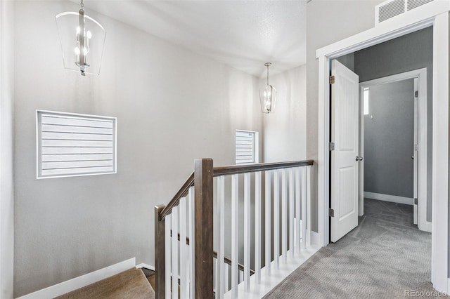 hall featuring carpet flooring and a chandelier