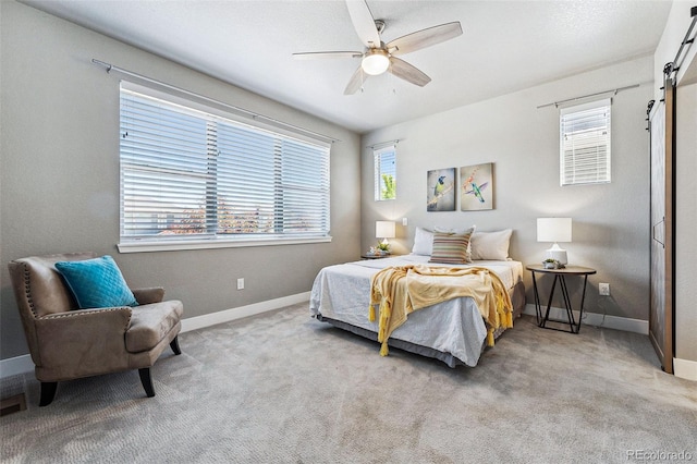 carpeted bedroom featuring a barn door and ceiling fan