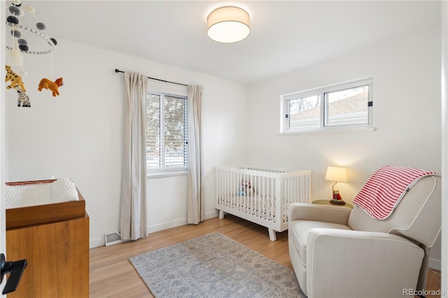 bedroom featuring a nursery area, light hardwood / wood-style flooring, and radiator