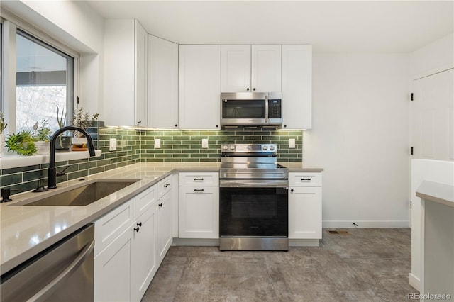 kitchen with backsplash, sink, white cabinets, and appliances with stainless steel finishes