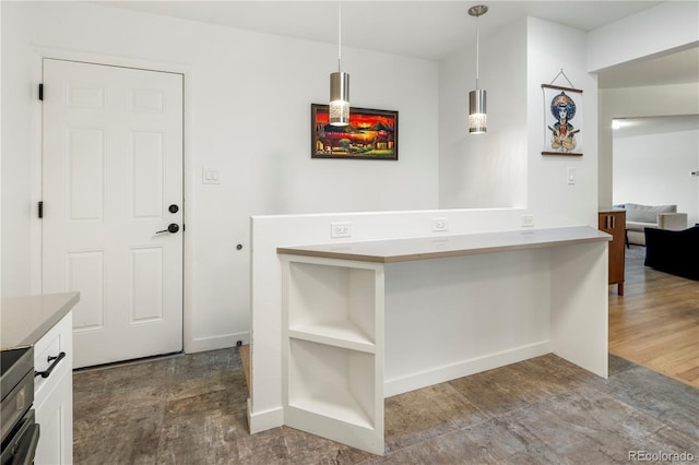 kitchen featuring wood-type flooring, white cabinetry, and hanging light fixtures