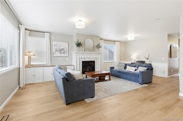 60 Stewart Way, Erie, CO 80516 - living area with light wood-style floors, a tiled fireplace, and a wainscoted wall