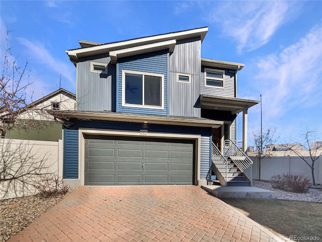 view of front of property with an attached garage, fence, and decorative driveway