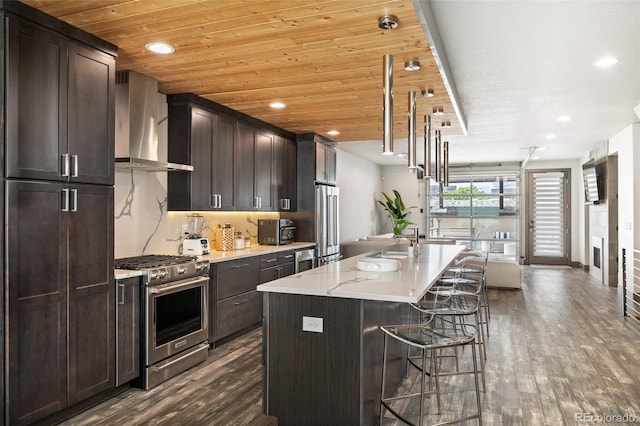 47 Harrison, Denver, CO 80206 - kitchen with high end appliances, wall chimney exhaust hood, dark wood-style floors, an island with sink, and recessed lighting