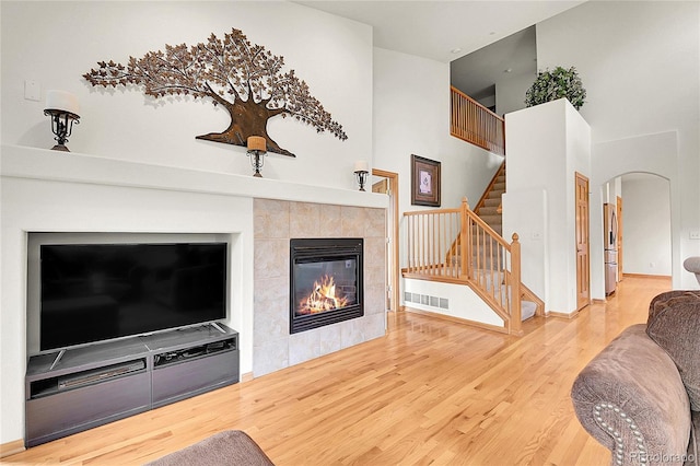 31139 Tahoe Ct, Evergreen, CO 80439 - living area with a high ceiling, wood finished floors, arched walkways, stairway, and a tile fireplace