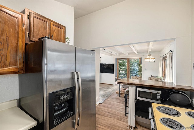 200 Crest Dr, Idaho Springs, CO 80452 - kitchen featuring appliances with stainless steel finishes, light wood finished floors, brown cabinets, beam ceiling, and decorative light fixtures