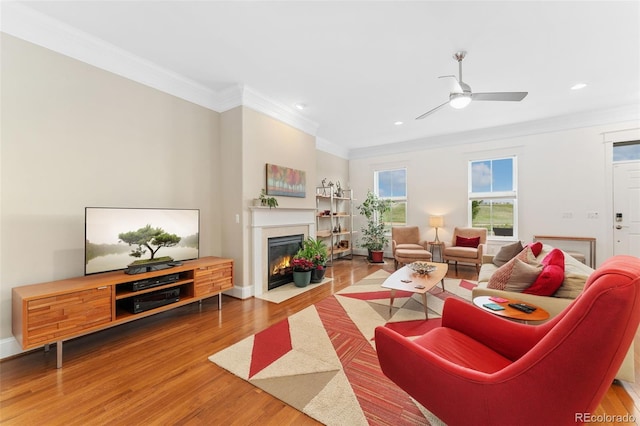 living area featuring a ceiling fan, recessed lighting, ornamental molding, a fireplace with flush hearth, and wood finished floors