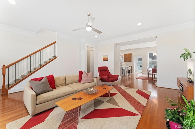 living room featuring ceiling fan, ornamental molding, stairs, and hardwood / wood-style floors