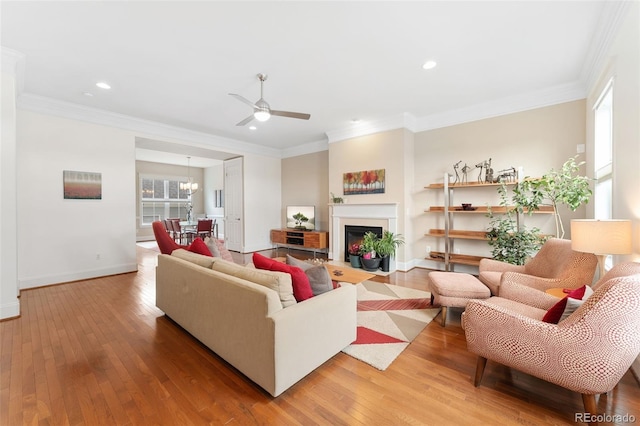 living room with crown molding, a ceiling fan, light wood-style flooring, and baseboards