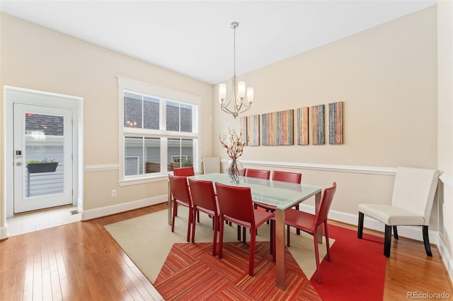dining room with a notable chandelier, baseboards, and wood finished floors