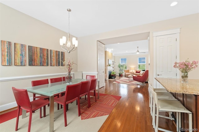 dining room with recessed lighting, ceiling fan with notable chandelier, and wood finished floors