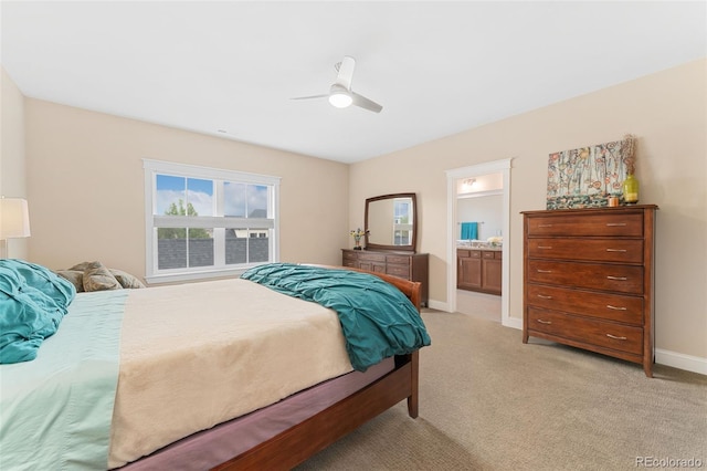 bedroom with baseboards, ensuite bath, a ceiling fan, and light colored carpet