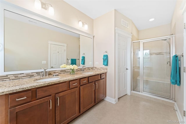 bathroom with double vanity, visible vents, a stall shower, and a sink