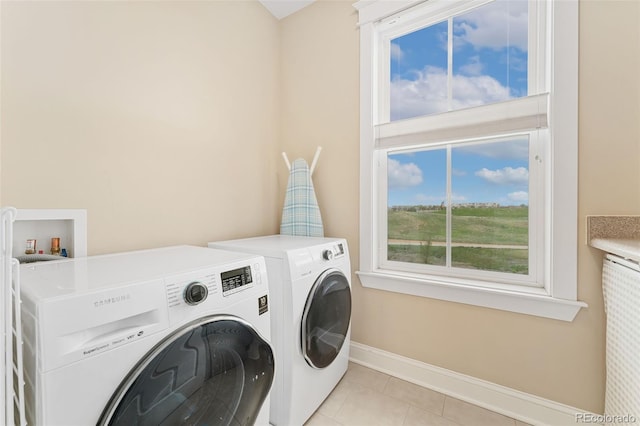 laundry area featuring baseboards, laundry area, light tile patterned floors, and independent washer and dryer