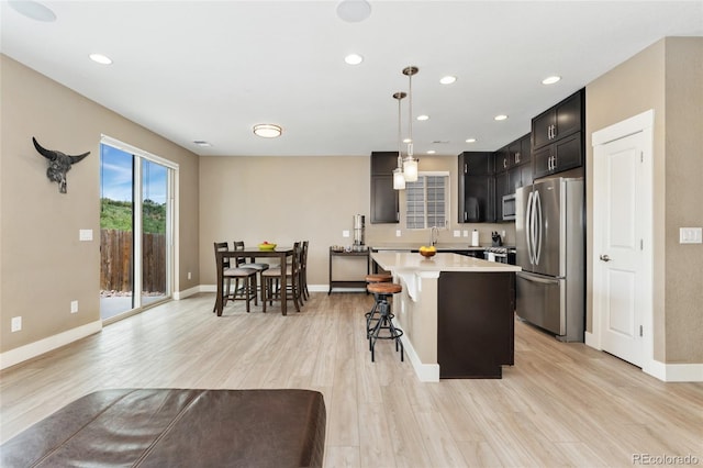 15061 W 70th Ave, Arvada, CO 80007 - kitchen featuring appliances with stainless steel finishes, light countertops, light wood-type flooring, a kitchen bar, and a center island