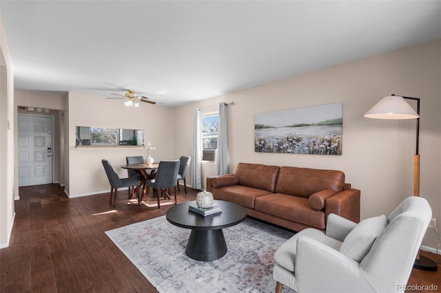 living area featuring baseboards, a ceiling fan, and dark wood-style flooring