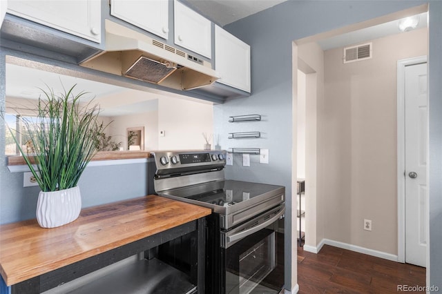 kitchen with dark wood-style flooring, visible vents, stainless steel range with electric cooktop, under cabinet range hood, and butcher block countertops