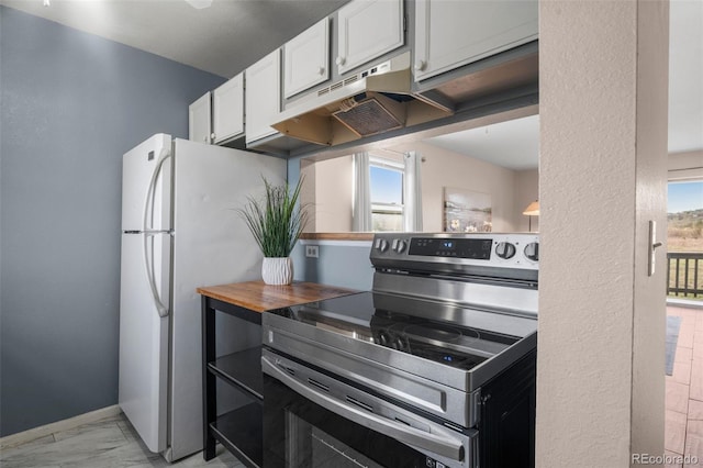 kitchen featuring white cabinets, freestanding refrigerator, marble finish floor, and stainless steel range with electric stovetop