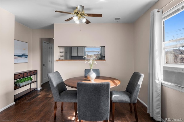 dining area with dark wood-type flooring, baseboards, ceiling fan, and visible vents