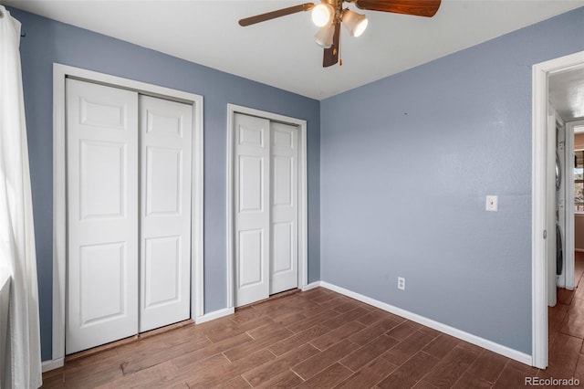 unfurnished bedroom featuring baseboards, ceiling fan, multiple closets, and wood finished floors