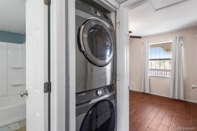 washroom with stacked washer and dryer, laundry area, and wood finished floors