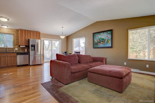 living room with lofted ceiling, light hardwood / wood-style flooring, and sink