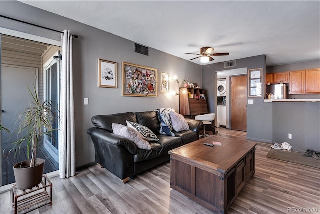 living room featuring stacked washer and dryer, hardwood / wood-style flooring, and ceiling fan