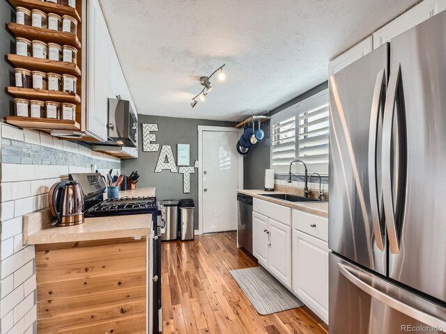 4747 S Elati St, Englewood, CO 80110 - kitchen with stainless steel appliances, light wood-style flooring, white cabinets, light countertops, and decorative backsplash