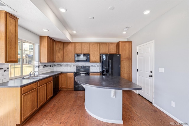 kitchen with dark hardwood / wood-style flooring, a center island, black appliances, and sink