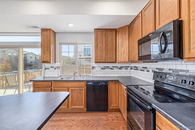 kitchen featuring backsplash, sink, black appliances, and hardwood / wood-style flooring