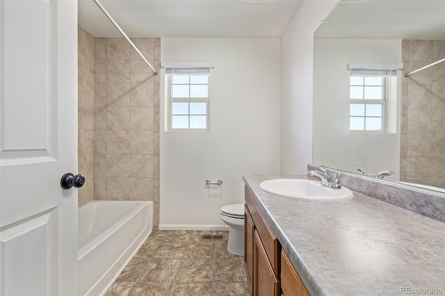 full bathroom featuring vanity, toilet, tiled shower / bath combo, and plenty of natural light