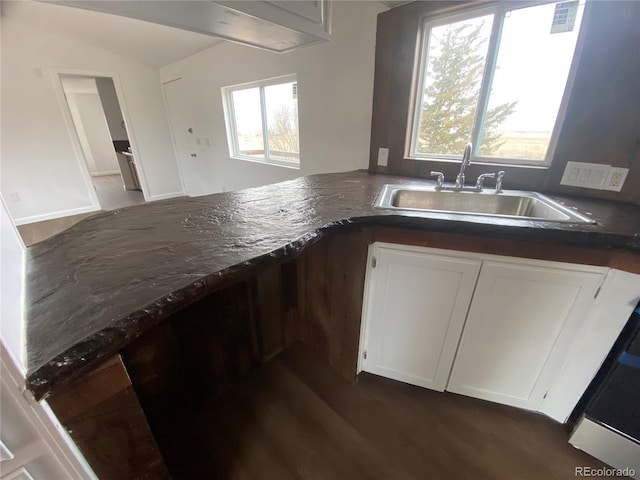 kitchen with vaulted ceiling, dark wood-type flooring, sink, and white cabinets