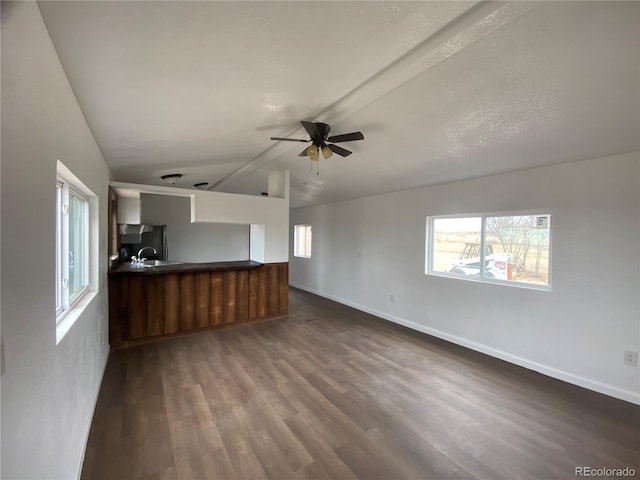 unfurnished living room featuring ceiling fan, plenty of natural light, dark hardwood / wood-style flooring, and vaulted ceiling