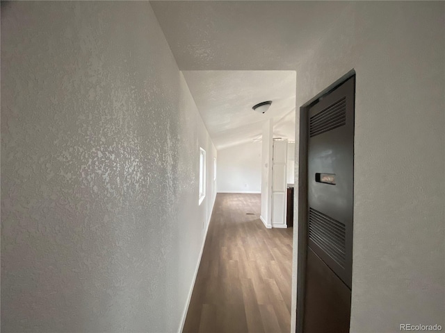 hallway featuring hardwood / wood-style flooring and vaulted ceiling