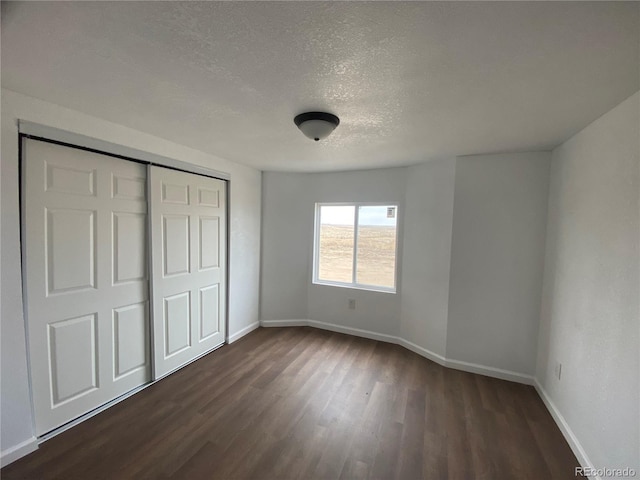 unfurnished bedroom featuring dark wood-type flooring, a closet, and a textured ceiling