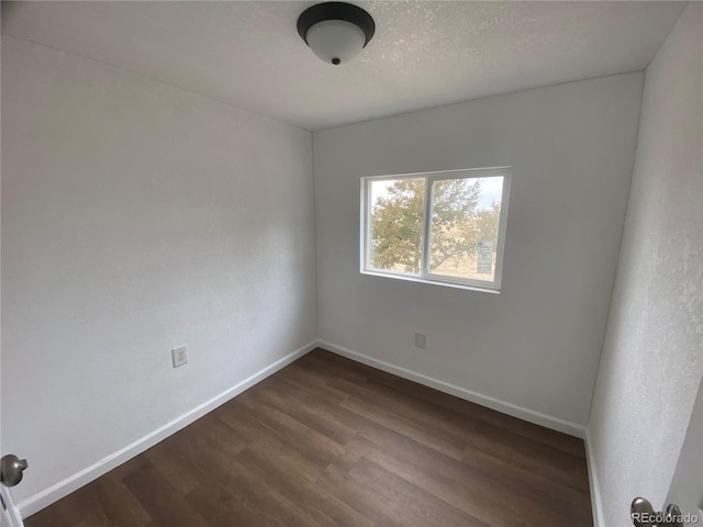 spare room with dark wood-type flooring and a textured ceiling