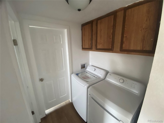 laundry area featuring cabinets, washing machine and clothes dryer, and dark hardwood / wood-style flooring