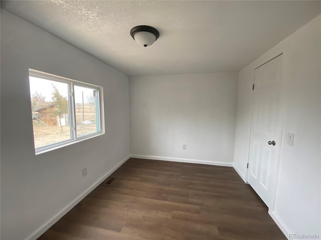 spare room with dark wood-type flooring and a textured ceiling