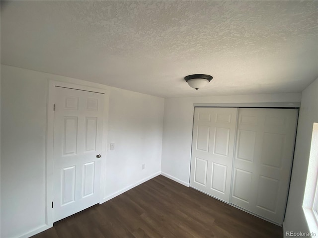 unfurnished bedroom with a closet, dark hardwood / wood-style floors, and a textured ceiling